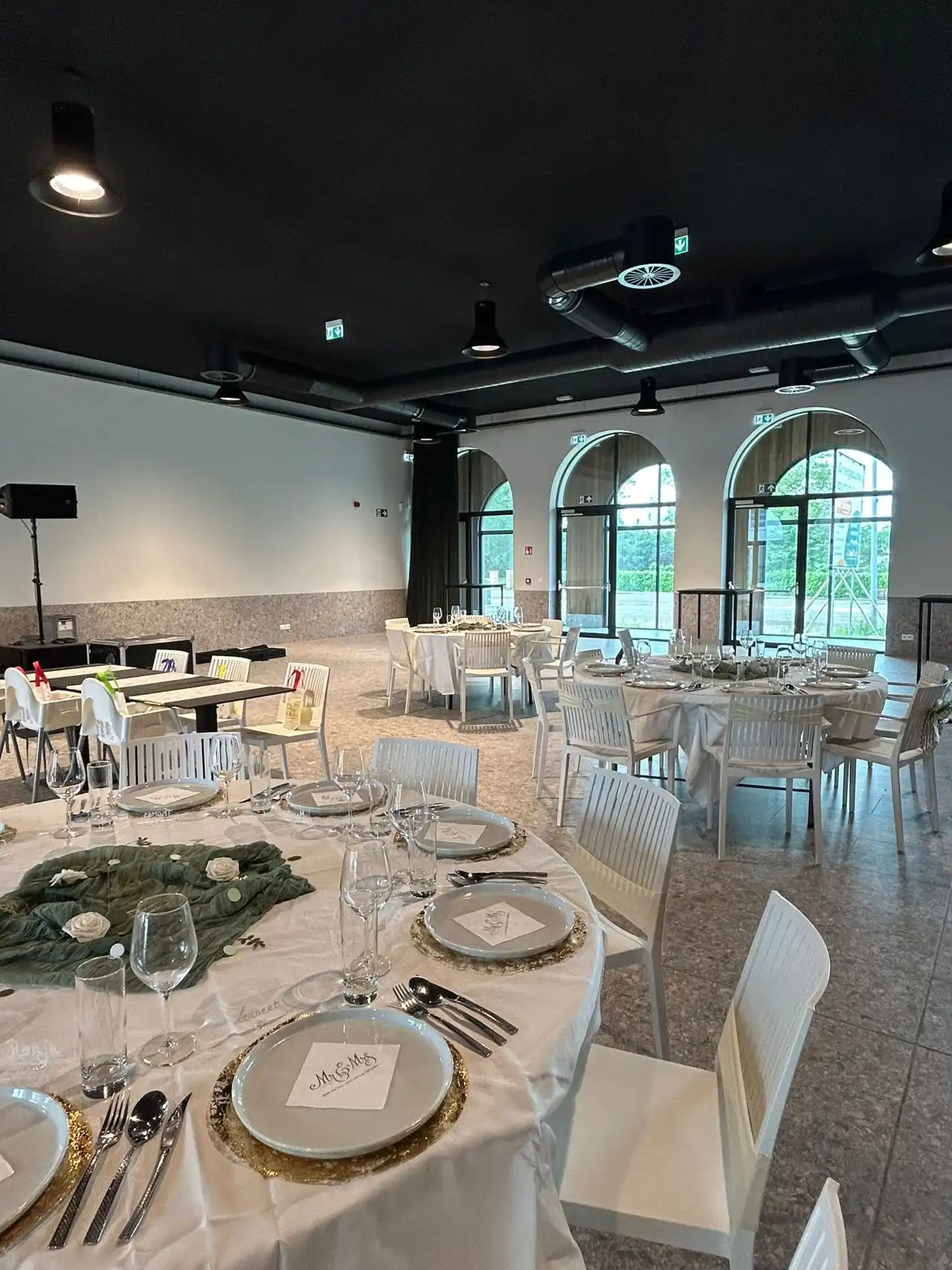 Feestzaal met feestelijk gedekte tafels en boogramen