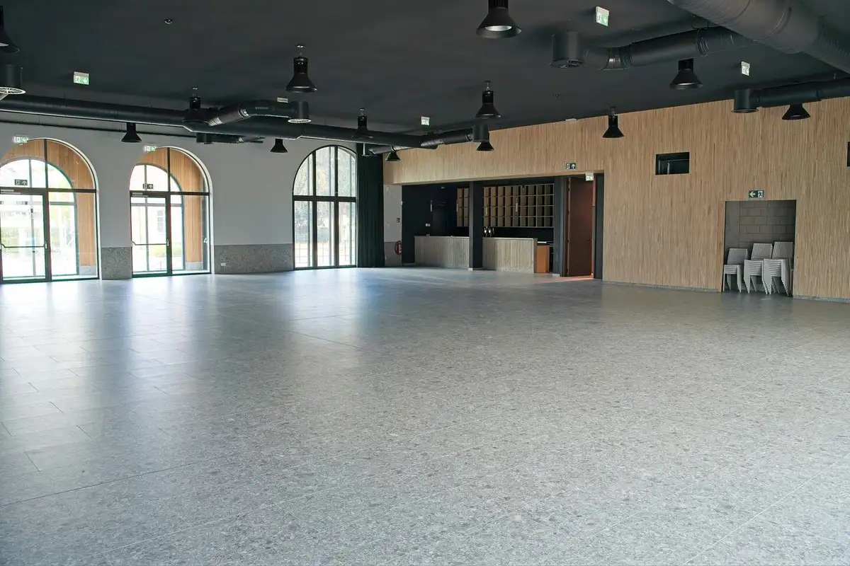 De grote feestzaal met boogramen en bar, klaar om naar jouw wens ingericht te worden